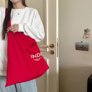 Detail of red canvas tote bag with white letter print and durable shoulder strap