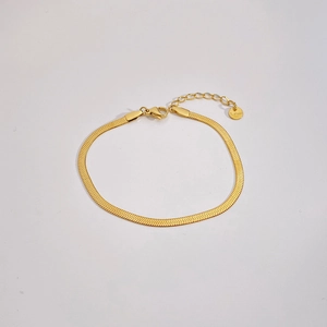 Macro detail of gold stainless steel flat snake chain bracelet with lobster clasp and tag