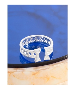 Macro shot of silver bow ring with hollow grid design on a marble stand