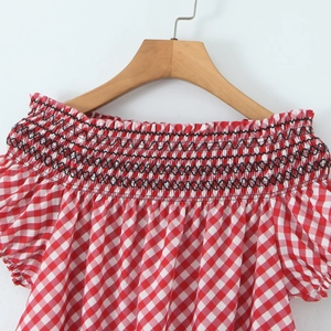 Détail du tissu à carreaux rouges et blancs avec décolleté élastique à smocks