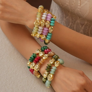 Close-up of colorful acrylic beaded bracelets with gold accents worn by a female model