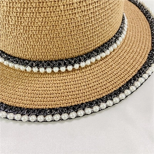 Detailed close-up of a flat-top straw hat featuring lace trim and elegant white pearls