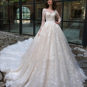 Elegant long-sleeved ivory lace ball gown wedding dress with a dramatic long train