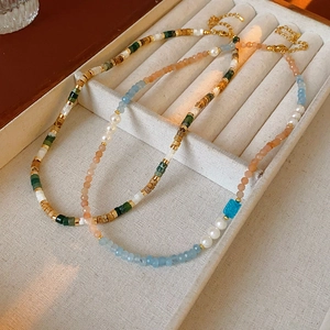 Detail of square aquamarine and pearl beaded necklaces with mixed color stones