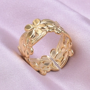 Close-up of golden stainless steel ring with embossed flower patterns on pink silk