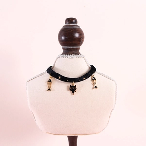 Detail of black velvet pet collar with gold cat and fishbone pendants and star prints