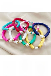 Detail of colorful heishi bead bracelets featuring baroque pearls on silk background