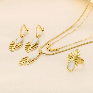Détail d'un ensemble de bijoux feuille de monstera dorée avec pierres œil de chat blanches