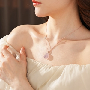 Close-up of a rose gold necklace featuring a soft pink chalcedony Buddha pendant on a model