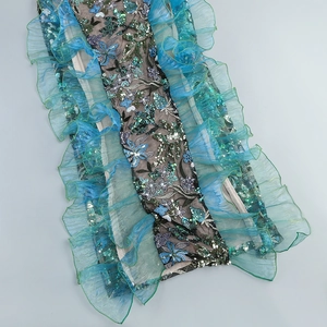 Détail de dentelle florale brodée avec paillettes sarcelles et tulle plissé sur robe