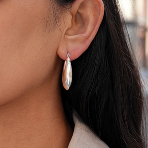 Close-up of polished silver teardrop earring on model showing high mirror finish