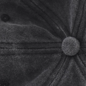 Macro shot of the top button and stitching details on a washed gray cotton baseball cap