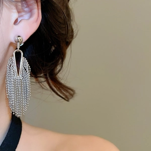 Macro view of silver fringe tassel earrings with delicate metal bead chains on model