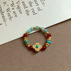 Vintage gold-plated ring with tiger eye stone and turquoise beads on textured background
