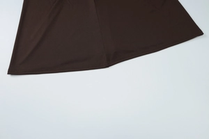 Close-up of the dark brown knitted fabric hem with detailed stitching and refined texture
