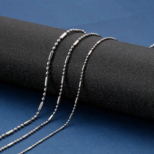 Détail d'un collier chaîne à boules en acier inoxydable argenté sur un support texturé