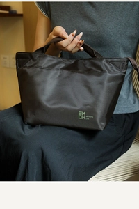 Dettaglio della borsa termica in nylon color caffè con finitura lucida e logo