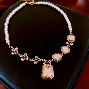 Detail of pearl necklace with geometric crystal pendants on black leather display