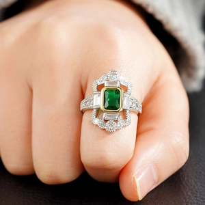 Detalle macro de anillo Art Deco con piedra verde corte esmeralda y diamantes geométricos