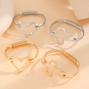 Detail of hollow heart and cross charm bracelets with spring coil texture in gold and silver