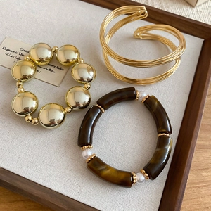 Gros plan sur le bracelet jonc doré et l'ensemble de bracelets perlés en acrylique