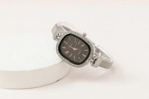 Close-up of elegant silver mesh strap watch with rhinestone bezel and black square dial