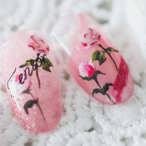 Pink rose press-on nails with glitter accents and elegant floral art on lace background