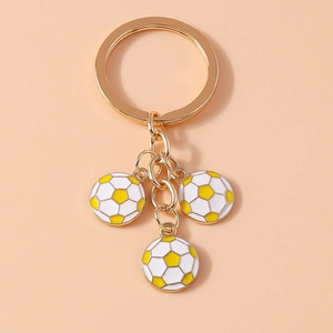 Detail of three white and yellow enamel football charms on a gold metal keychain