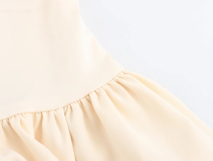 Detail showing elegant beige fabric texture and ruched waist stitching on a French dress