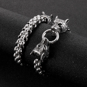 Detailed view of silver double wolf head clasps on a braided leather cord bracelet for men