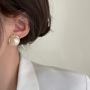 Elegant large round pearl stud earrings with gold base worn on ear for stylish look