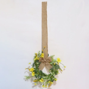 Detail of Easter wreath with yellow daisies, green leaves, and rustic burlap bow hanger