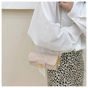 Detail of beige quilted cylinder bag with gold chain strap worn with a stylish outfit