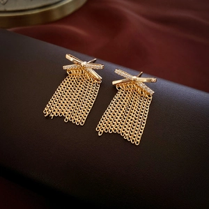 Macro shot of gold-plated tassel earrings with zircon bow knots and long chains
