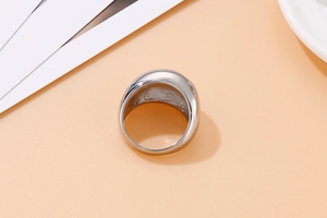 Close-up of a wide polished stainless steel dome ring on a minimalist background