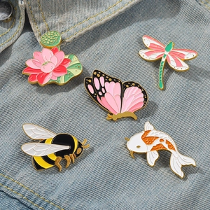 Detail of five enamel pins featuring lotus and animals on a blue denim jacket
