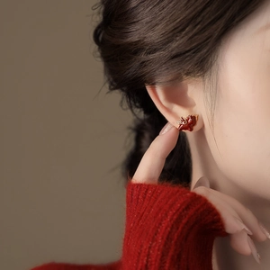 Gros plan d'un clou d'oreille pégase en émail rouge porté par un mannequin