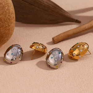 Close-up of 18K gold and silver oval earrings with colorful zircon stones on stones
