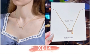 Dettaglio collana in titanio dorato con ciondolo LOVE e cuore su cartoncino per gioielli
