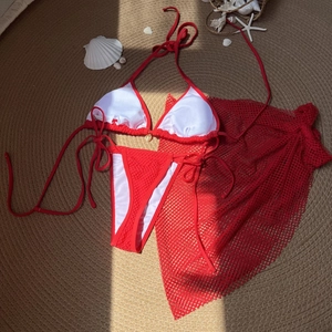 Three-piece red bikini set with halter top, high cut bottoms and mesh sarong cover-up