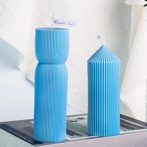Bougies parfumées bleu clair à rayures verticales posées sur un magazine de mode
