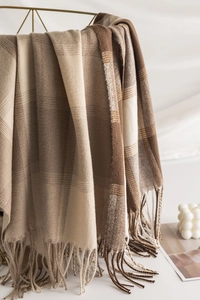 Detail of soft plaid scarf with fringe tassels draped on a golden basket display