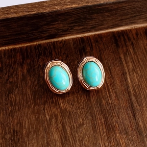 Gros plan de boucles d'oreilles vintage en turquoise ovale avec bordure rose