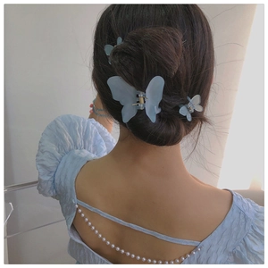 Detail of matte blue butterfly hair clips in large and small sizes worn on hair