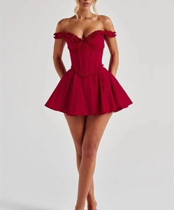 Detail of red off-shoulder mini dress with corset bodice and ruffle hem in studio lighting