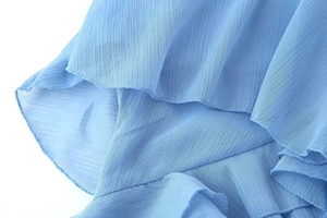 Detail of light blue chiffon fabric featuring delicate ruffled edges and layered textures