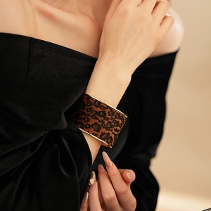 Close-up of a wide leopard print bangle with gold metal edges on a velvet sleeve
