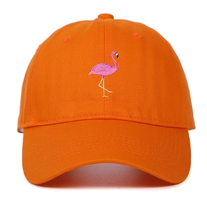Detailed close-up of vibrant pink flamingo embroidery on an orange cotton baseball cap