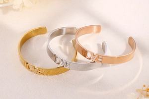 Detailed view of LOVE engraved cuff bracelets in gold, silver and rose gold finishes