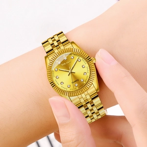 Close-up of golden quartz watch with rhinestone indices and polished steel link band